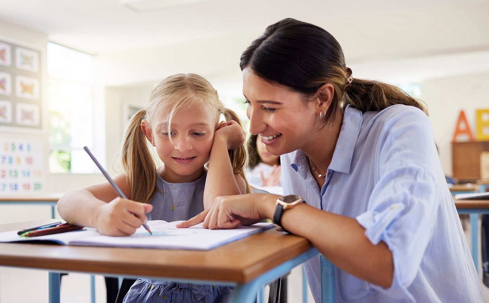 Teacher, learning and helping girl in classroom for drawing, studying or assessment. Teaching, development and kid or student with happy woman for education assistance with notebook in kindergarten, Neuropsychological Evaluations, Wayne, PA